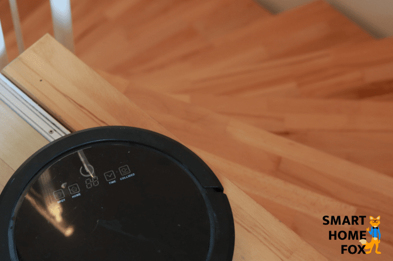 Robot vacuum stands in front of a staircase
